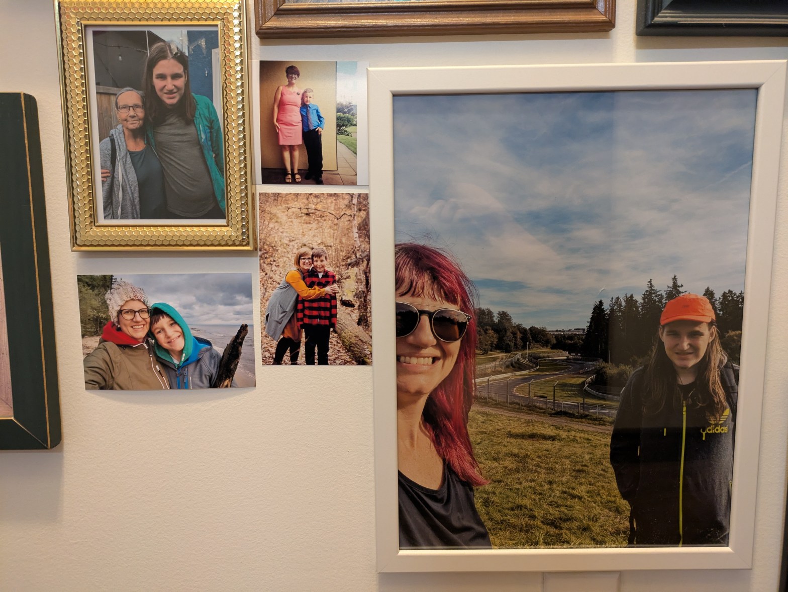 Printed photos of Lisa and her son some in picture frames mounted on an ivory painted wall
